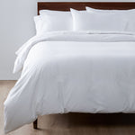 Neatly made bed with Fix Linens white cotton bedding in a simple room, showing simple, stylish Airbnb-ready design.