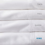 Stack of Fix Linens sheets showing embroidery differenced in sheet sizes. King size is highlighted in blue type.
