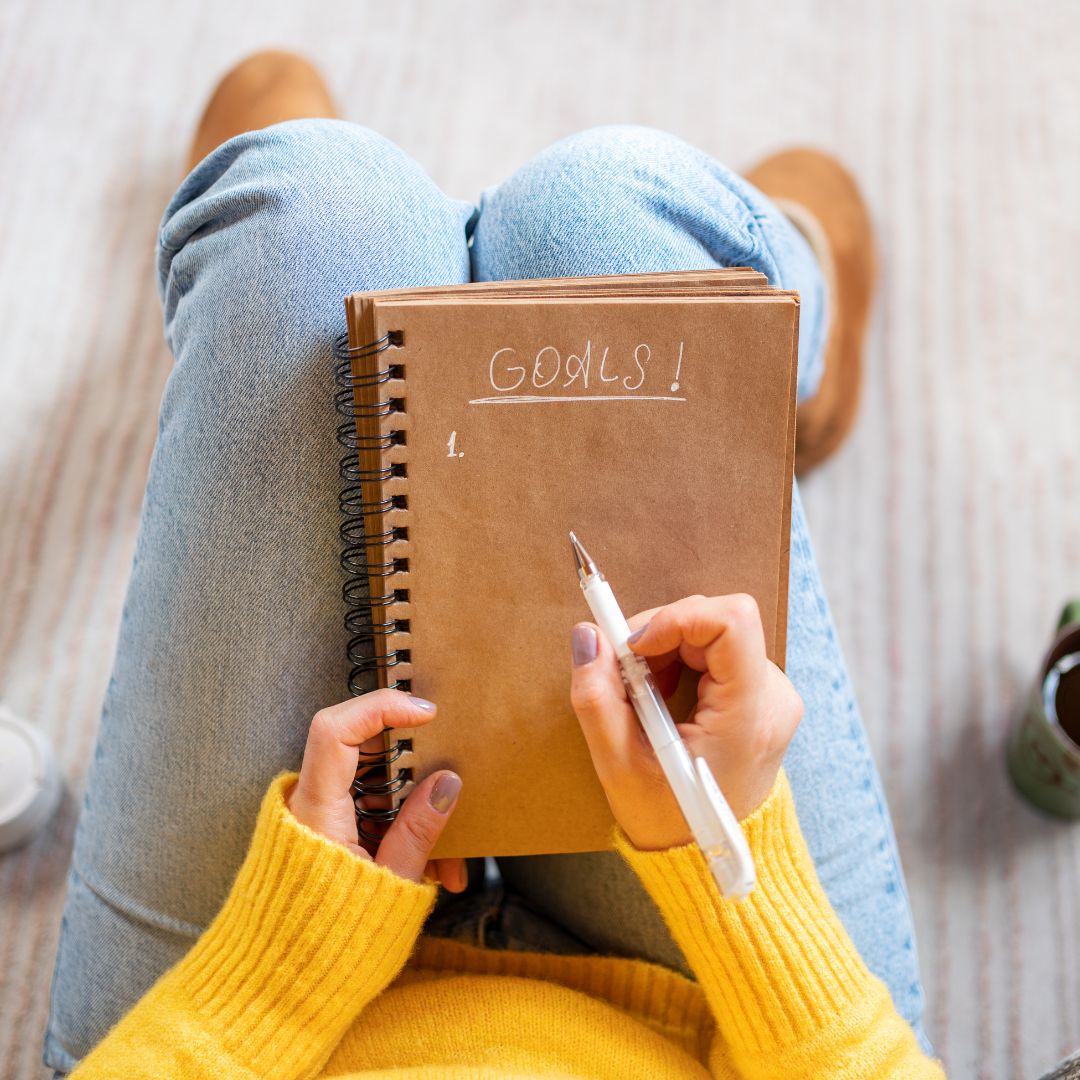 a girl holding a notebook tht says goals