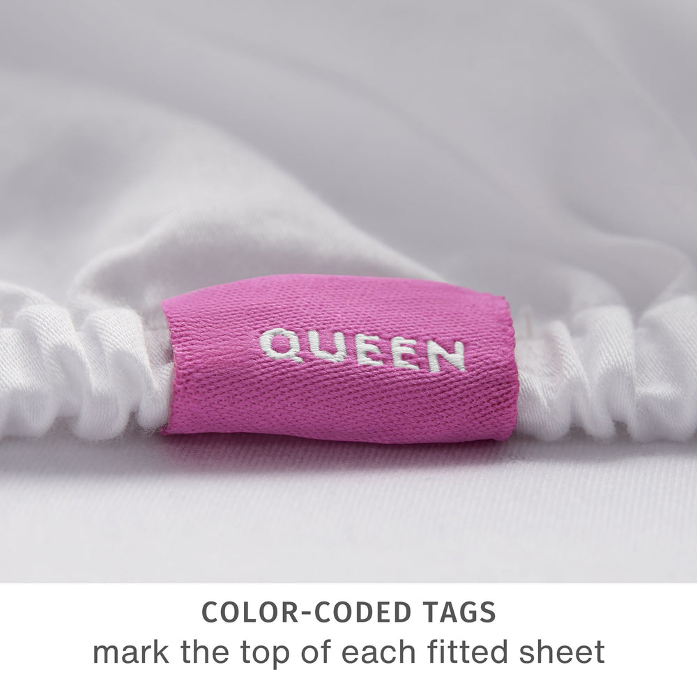 
                  
                    close up detail of a purple tag reading “QUEEN”. This tag marks the top-center of the fitted sheet
                  
                